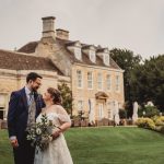 Bride and groom outside a historic manor house.