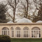 Elegant glass-domed pavilion in autumnal garden setting.