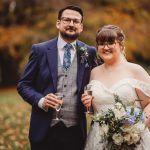 Bride and groom smiling with champagne outdoors.