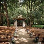 Outdoor woodland wedding ceremony with benches and altar.