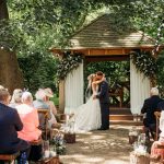 Outdoor wedding ceremony with kissing couple