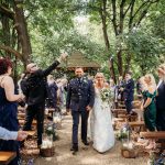 Bride and groom walking down outdoor aisle.