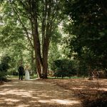 Couple walking in a sunlit forest pathway.