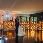 Bride and groom dancing, illuminated 'Mr & Mrs' sign