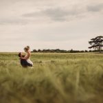 Couple embracing in a picturesque field landscape.