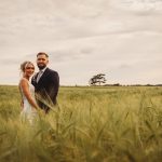 Couple standing in a grassy field.