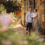 Couple standing outside rustic house in garden