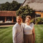 Couple smiling in sunny garden setting.