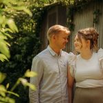 Couple smiling in sunlit garden.