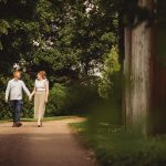 Couple walking hand-in-hand on a tree-lined path.