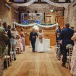 Bride and groom walk down the aisle, guests applaud.