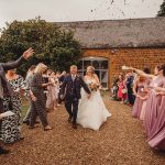 Newlyweds walking through confetti thrown by guests.