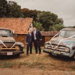 Two men in suits with vintage trucks decorated.