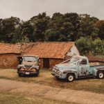 Vintage trucks by rustic buildings, wedding ribbons attached.