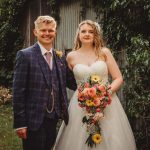 Bride and groom smiling with floral bouquet.