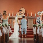 Bride and groom kneeling during church wedding ceremony.