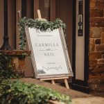 Welcome wedding sign with floral frame outside venue entrance.