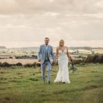 Bride and groom walking in countryside field