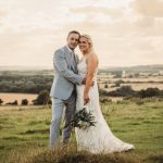 Bride and groom standing in a scenic field