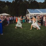 Wedding guests watch bouquet toss in garden