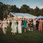 Bride and bridesmaids celebrate at outdoor wedding reception.