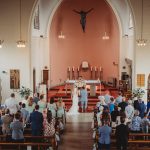 Wedding ceremony in church with priest and guests.