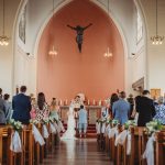 Wedding ceremony inside church, guests seated.