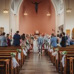 Bride and groom walking down church aisle, guests applauding.