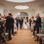 Bride and groom walk down wedding aisle.