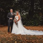 Bride and groom in autumn forest wedding scene.