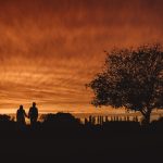 Silhouette couple holding hands at sunset.