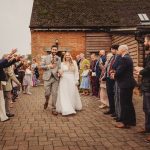 Newlyweds leaving ceremony, guests throwing confetti.