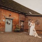 Wedding couple with dog outside rustic barn