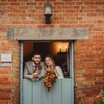 Couple at rustic barn wedding ceremony entrance.