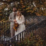 Bride and groom on autumn bridge, sunflower bouquet.