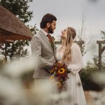 Bride and groom smiling in garden wedding scene.