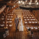 Couple in rustic barn wedding venue with chairs.