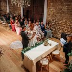 Bride and groom at ceremony with guests seated.