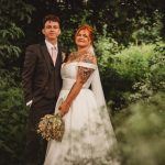 Bride and groom in lush garden setting.