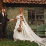 Couple in wedding attire by rustic green doors.