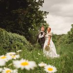 Couple in wedding attire surrounded by lush greenery