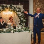 Wedding speech with bride and groom applauding.