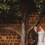 Bride and groom standing by a tree.