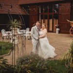 Wedding couple smiling in courtyard setting.