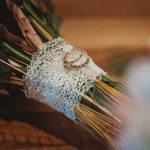 Wedding rings on lace-wrapped bouquet stems.