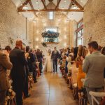 Couple exits wedding ceremony, guests applauding.