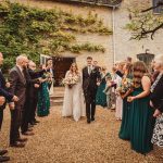 Bride and groom exiting wedding ceremony, guests celebrating.