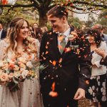 Bride and groom showered with confetti, smiling guests.