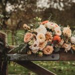 Rustic autumn bouquet on wooden fence outdoors.