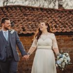 Smiling couple holding hands by rustic building